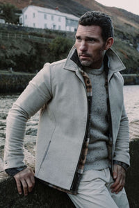Herrenmodel das ein Pullover von Peregrine aus Merinowolle trägt mit einer Jacke drüber.